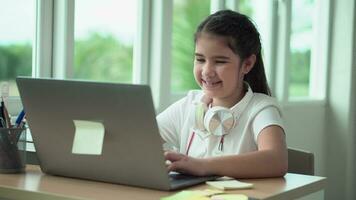 niño niña sonrisa disfrutar e-learning en computadora cuaderno con para risa a gracioso comunicación y estudiar en línea o aprender desde hogar a jugar ordenador portátil por espalda a colegio video