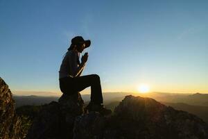 Silhouette of The girl  prayed  in the mountains to think of a loving God, we praise God. photo