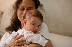 Selective focus on a newborn baby in the hands of a delightful woman, a happy loving mother gently hugging her baby boy. photo