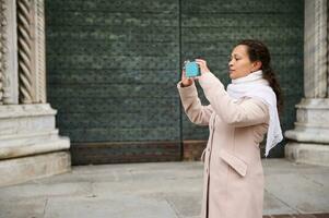 Business woman holding mobile phone, photographing the city square in Italian city of Como in Lombardy photo