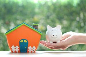 Finance, Model house with piggy bank and stack of coins money on natural green background,Business investment and real estate concept photo