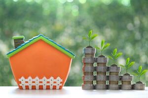 Model house and trees growing on stack of coins money on natural green background,Business investment and real estate concept photo