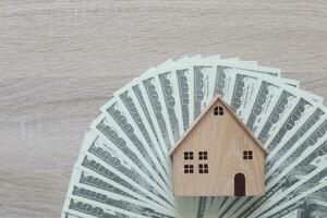 Model house and usd dollar money on wooden background,Save money for prepare in future and family finance concept photo