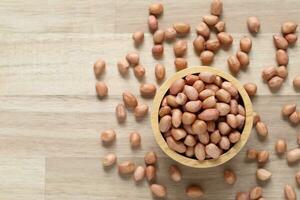 Top view of peanuts in a bowl on wooder background, Healthy eating concept photo