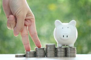 Piggy bank and stack of coins money on natural green background, Save money for prepare in future and pension retirement concept photo