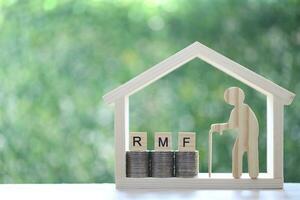 RMF - Retirement Mutual Fund,Senior with RMF word on stack of coins money in model house on natural green background, Save money for prepare in future and pension retirement concept photo