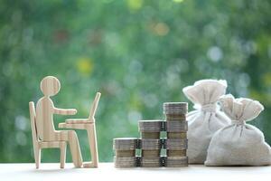 Investment and business concept,Man using laptop computer with stack of coins money on natural green background,Investors strategy photo