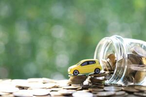 modelo de coche en miniatura en la creciente pila de monedas dinero en el fondo verde de la naturaleza, ahorrando dinero para el coche, finanzas y préstamo de coche, inversión y concepto de negocio foto