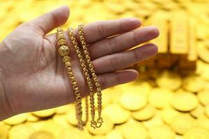 Gold necklaces and stack of coins money on yellow background, Business investment and Saving money for prepare in future concept photo