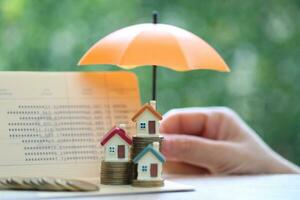 Protection, Model house on stack of coins money with the umbrella on nature green background,Finance insurance and Safe investment concept photo