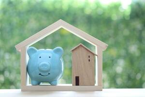 Finance, Model house with piggy bank and stack of coins money on natural green background,Business investment and real estate concept photo