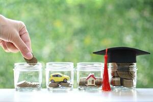 Woman hand putting a coin into the glass bottle on green background, Finance, Save money for prepare in future and education concept photo