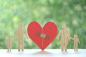 Divorce lawyer Or Attorney, Broken red heart with husband and wife splitting children on natural green background,Joint child custody and alimony concept. photo