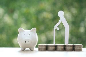 Mutual fund,Senior man on stack of coins money and piggy bank on natural green background, Save money for prepare in future and pension retirement concept photo