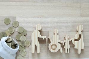 Senior man and people on wheelchairs with pregnant woman with stack of coins money on wooden background, Save money for handicapped person and pension concept photo