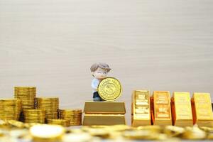 Business man on gold bar and gold coin money on wooder background,Business investment and Saving money for prepare in future concept photo