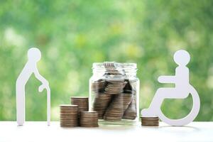 Mutual fund,Senior man and wheelchair user with stack of coins money in glass bottle on natural green background, Save money for handicapped person and pension retirement concept photo