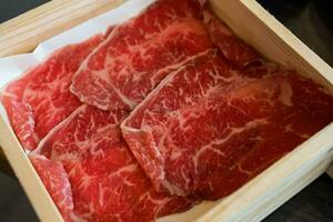 Rare sliced beef with marbled texture served on wood box photo