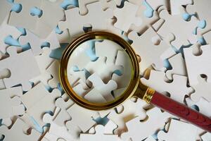 magnifying glass and on the missing puzzle piece. photo illustration concept of searching for and recruiting new employees