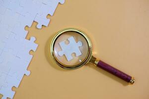 magnifying glass and on the missing puzzle piece. photo illustration concept of searching for and recruiting new employees