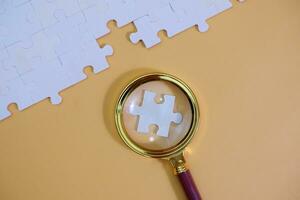 magnifying glass and on the missing puzzle piece. photo illustration concept of searching for and recruiting new employees