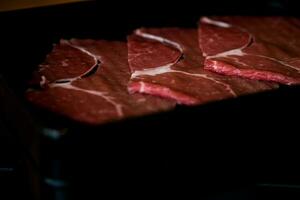 Close up of raw meat in black tray. photo