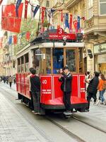 16 of April 2023 - Istanbul, Turkey -City life, the people and famous red tram on Istiklal pedestrian street photo