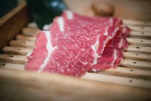 Sliced raw beef place in a row on a wood tray. photo