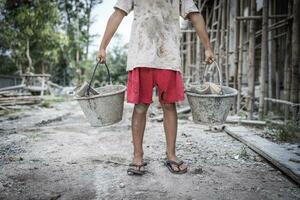 niños forzado a trabajo difícil a construcción sitio, niño labor concepto, pobre niños víctimas de humano trata proceso, pobreza, niño abuso. foto