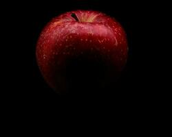 bright, vividly colored red apple on a black background during a studio photo session in the winter of 2023