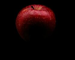 bright, vividly colored red apple on a black background during a studio photo session in the winter of 2023