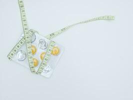 Measuring tape and pills isolated on white background. Top view. diet concept for a healthy lifestyle photo