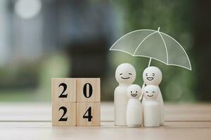 2024 Happy New Year. Budget planning, Life assurance, Plan for Protection against a possible eventuality. Family with smiling face and umbrella symbol of security or insurance with block number 2024. photo