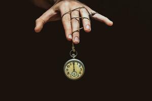 Old clock showing time under hand control for motivation or business concept photo