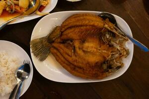 A dish of crispy Thai style deep fried whole sea bass fish photo
