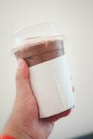 A glass of iced Mocha coffee wrapped by white tissue paper photo