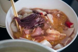 Closeup hand mix of fresh marinated pork on white bowl, set of ingredients for Thai style barbecue grill. photo