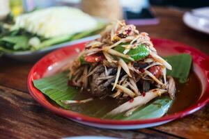 Spicy papaya salad with salted crab and Fermented fish served on Thai style tray photo