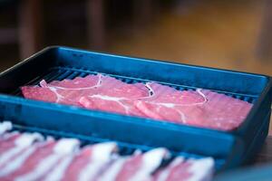 Raw freshly thin beef for Japanese sukiyaki served on long black tray photo