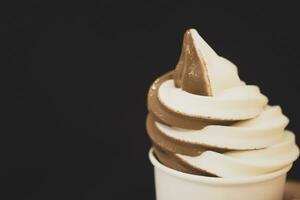 Hand holding takeaway cup with swirl soft serve ice cream photo