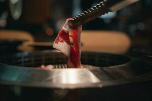 Bbq tongs keep premium slices of raw beef photo