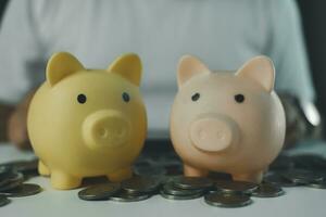 Pink and yellow fat piggy bank with many coin on human background for use finance. photo