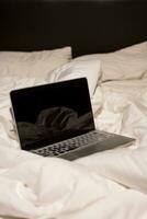 Laptop computer in bed with crumpled. photo