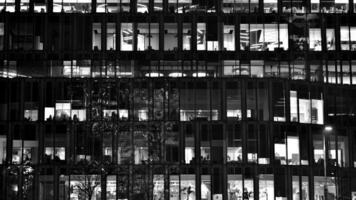 Pattern of office buildings windows illuminated at night. Glass architecture ,corporate building at night - business concept. Black and white. photo