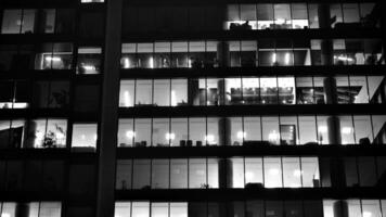 Pattern of office buildings windows illuminated at night. Glass architecture ,corporate building at night - business concept. Black and white. photo