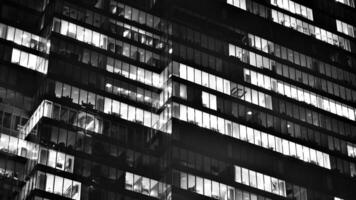 Pattern of office buildings windows illuminated at night. Glass architecture ,corporate building at night - business concept. Black and white. photo