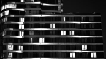 Pattern of office buildings windows illuminated at night. Glass architecture ,corporate building at night - business concept. Black and white. photo