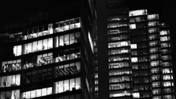 Pattern of office buildings windows illuminated at night. Glass architecture ,corporate building at night - business concept. Black and white. photo