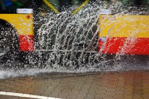 Splashes from under the wheels of the bus during heavy rain. Blurred bus. photo