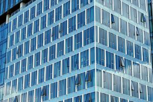 vaso edificio con transparente fachada de el edificio y azul cielo. estructural vaso pared reflejando azul cielo. foto